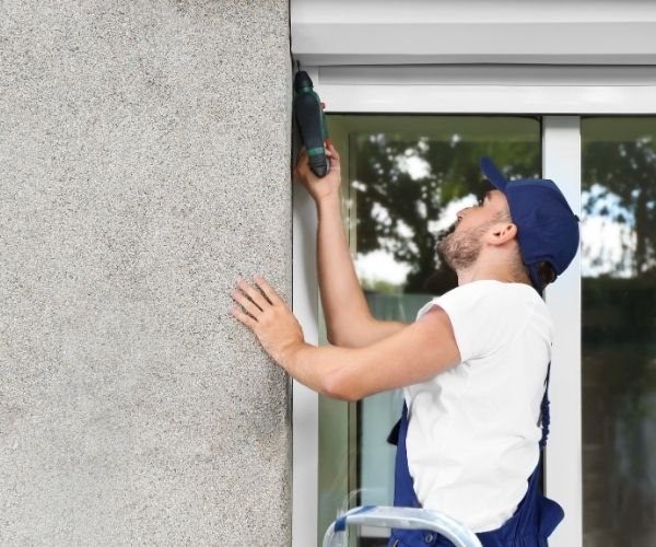 Techniker von Rollladen Rudolf montiert einen Rollladenkasten am Fenster